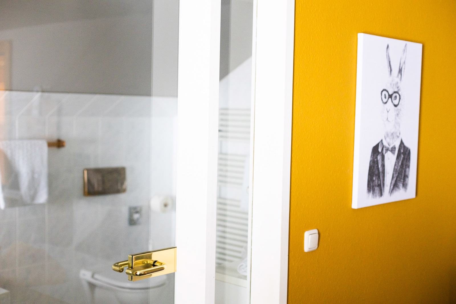 Blick ins Bad, Bild eines Hasen an gelber Wand in einem Scesa-Zimmer