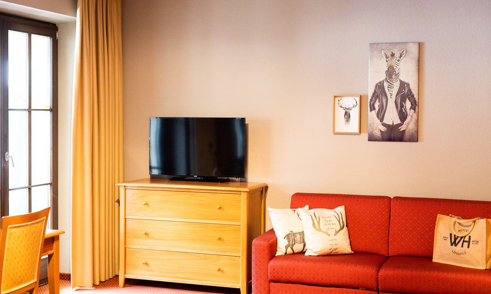 Rotes Sofa und Kommode mit Fernseher in einem Scesa-Zimmer