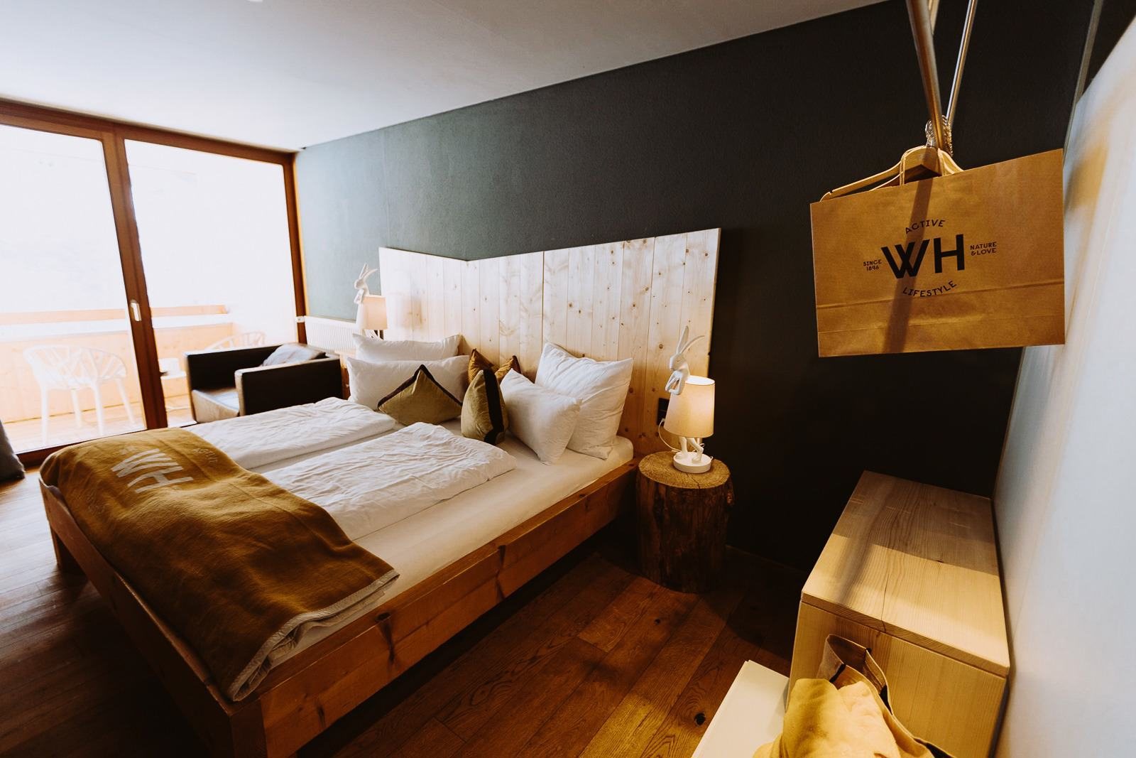 Doppelbett aus Brandner Fichte vor der Balkontür in einem Alpinista-Zimmer im Walliserhof