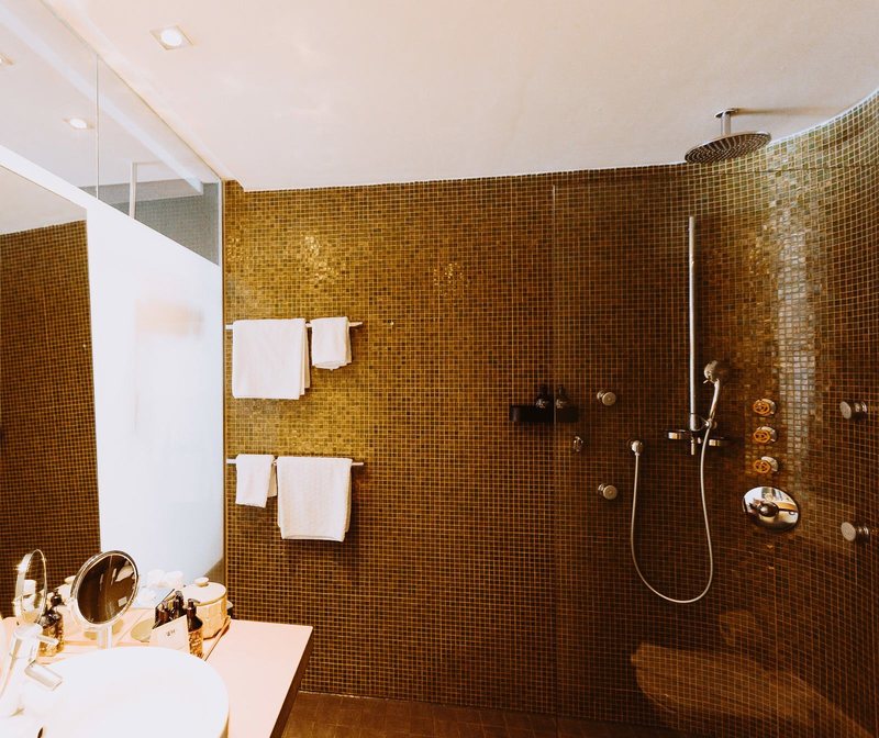 Bad mit goldenem Mosaik und Dusche in einem Alpinista-Zimmer im Walliserhof