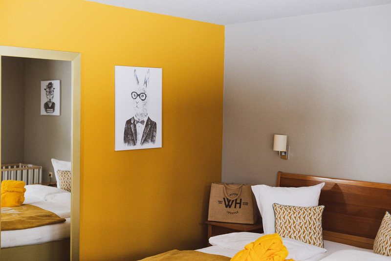 Scesa Kunterbunt · Doppelbett vor gelber Wand