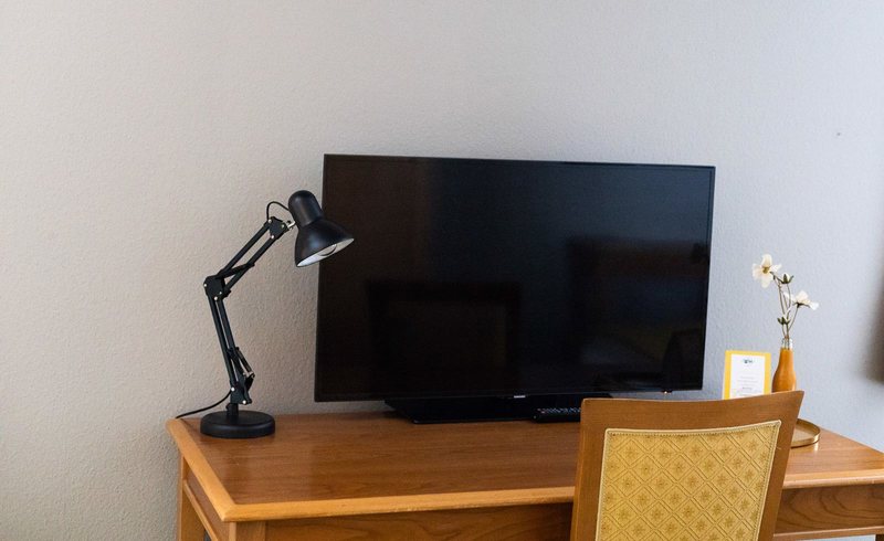 Schreibtisch mit Fernseher und Lampe in einem Scesa-Zimmer