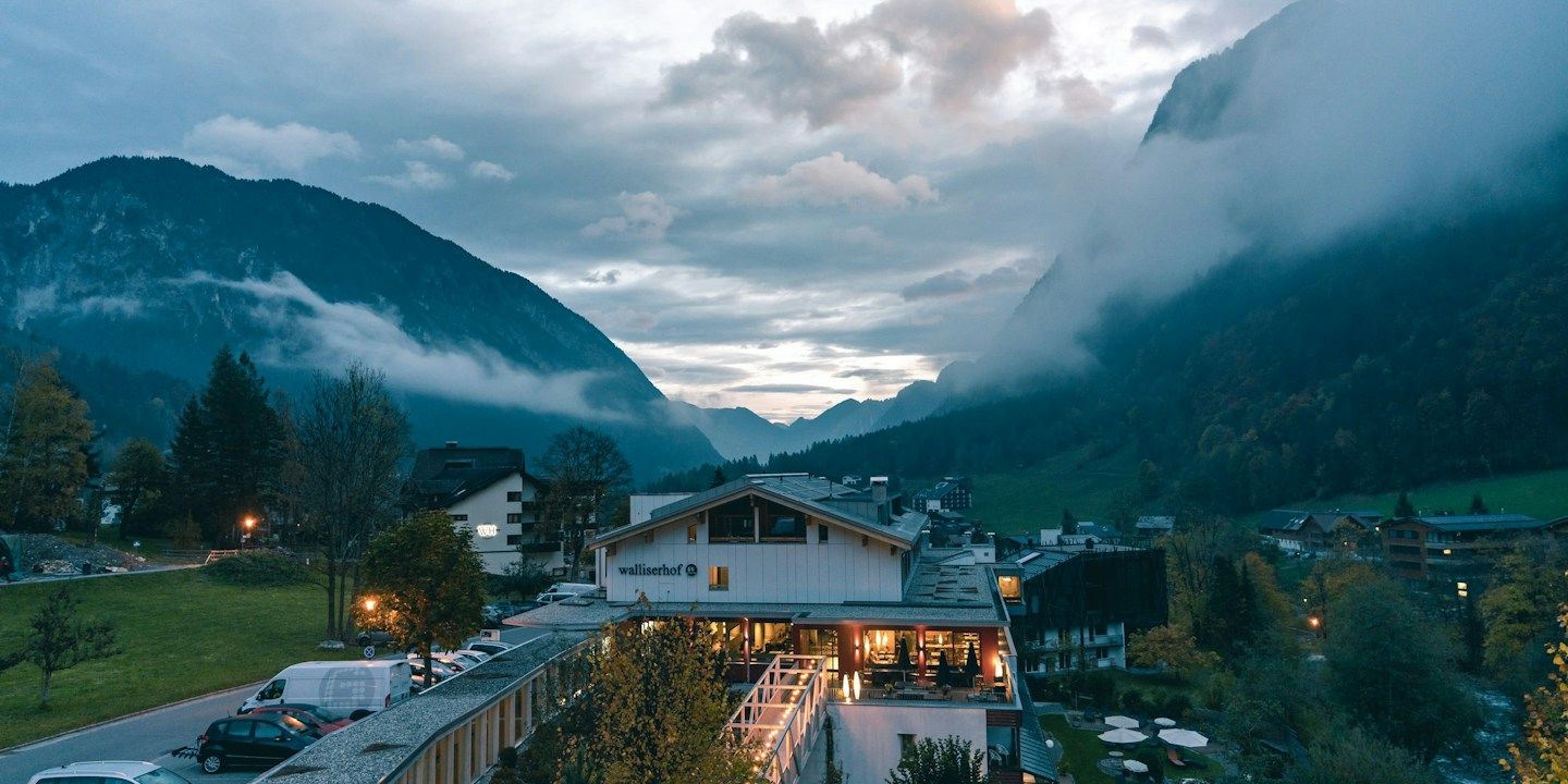 Eine malerische Ansicht von Bergen, einem Hotel und bewölktem Himmel in der Dämmerung.