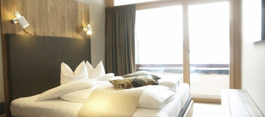 Ein gemütliches Hotelzimmer mit einem großen Bett, Holzakzenten und einem Fenster mit Vorhängen.