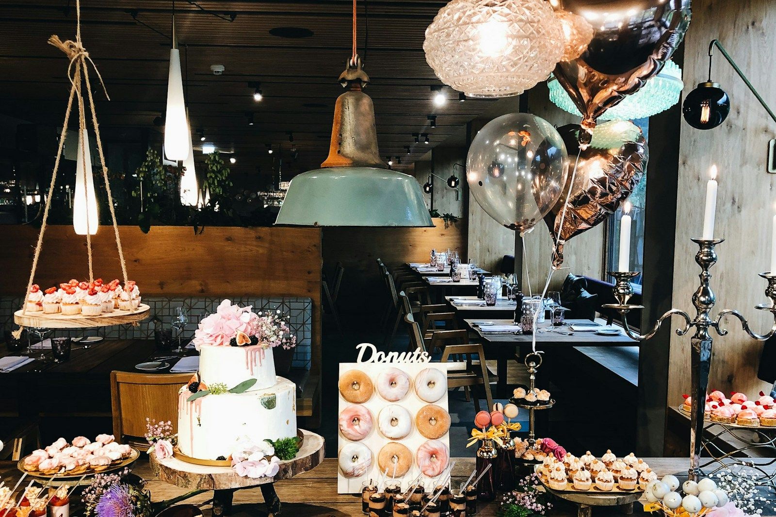 Ein Desserttisch mit einer mehrschichtigen Torte, Donuts und verschiedenen Leckereien in einem stilvollen Restaurant.
