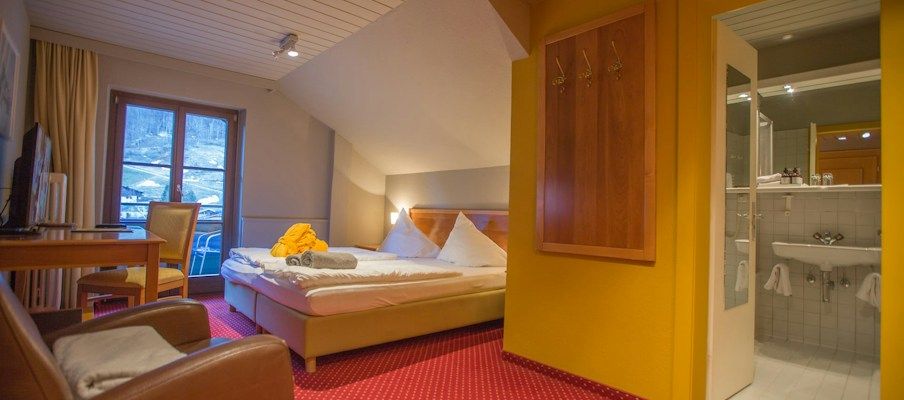 Gemütliches Hotelzimmer mit einem Bett, Schreibtisch und Modernem Badezimmerbereich.
