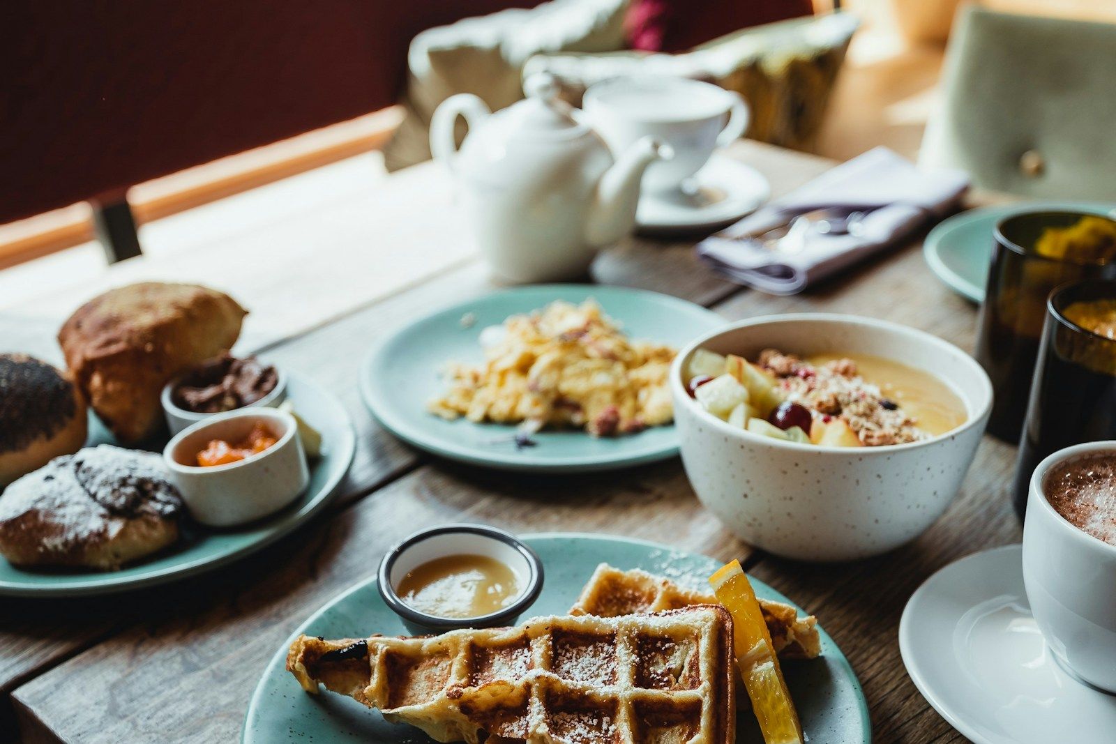 Ein Tisch mit einem Frühstücksangebot, einschließlich Waffeln, Obst, Gebäck und Getränken.