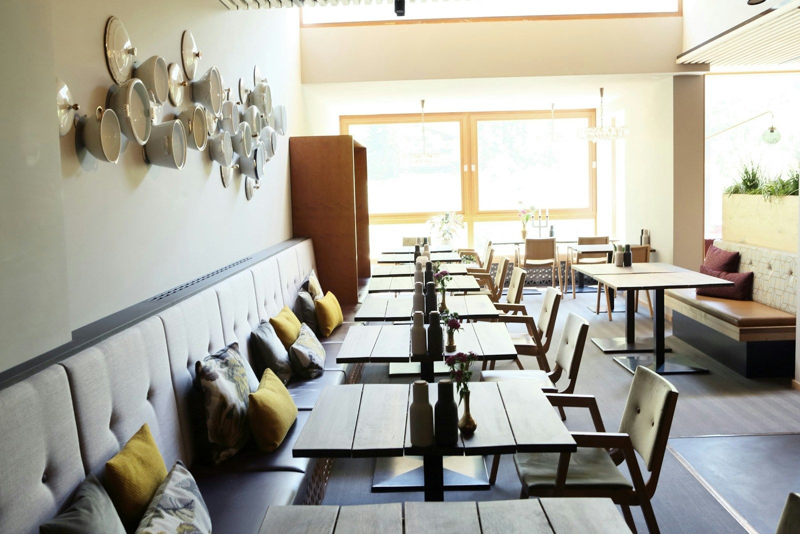 Modernes Restaurantinterieur mit Holztischen, gemütlichen Sitzgelegenheiten und dekorativen Wandtellern.